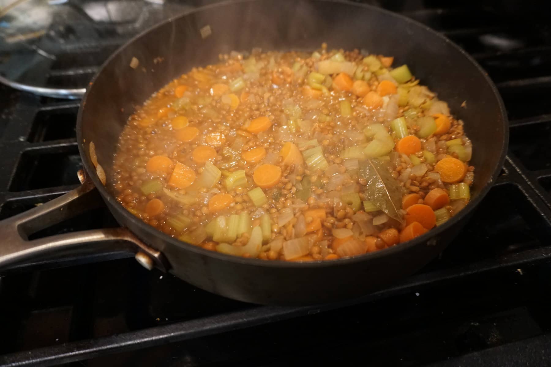 lentils simmering in a pan with carrots celery and onions