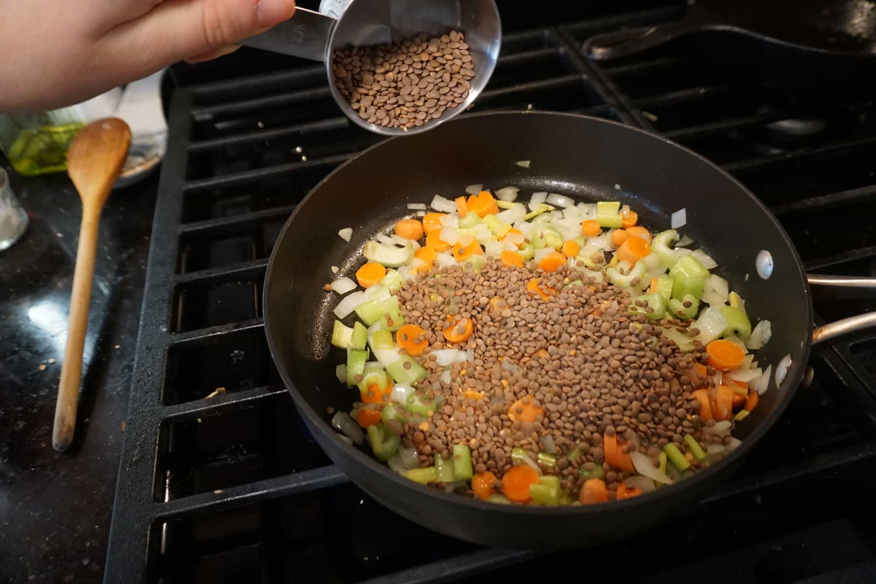lentils cooking in a skillet on the stove with carrots, onions, and celery