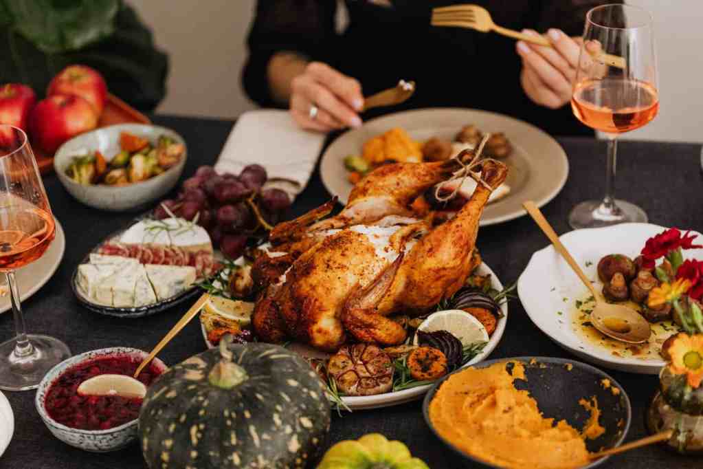 roasted turkey on white ceramic plate with other sustainable Thanksgiving recipes