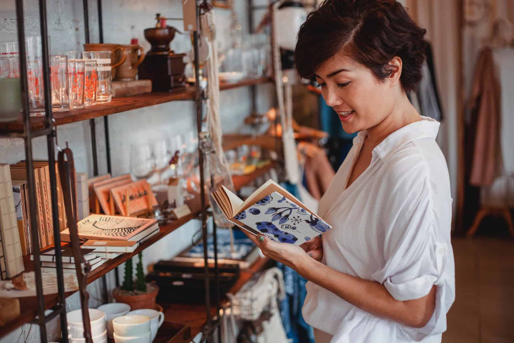 gorgeous asian young lady reading novel in vintage boutique