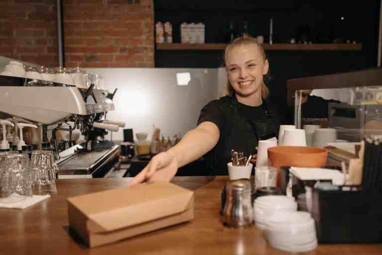 smiling woman in black crew neck t shirt handing out a box