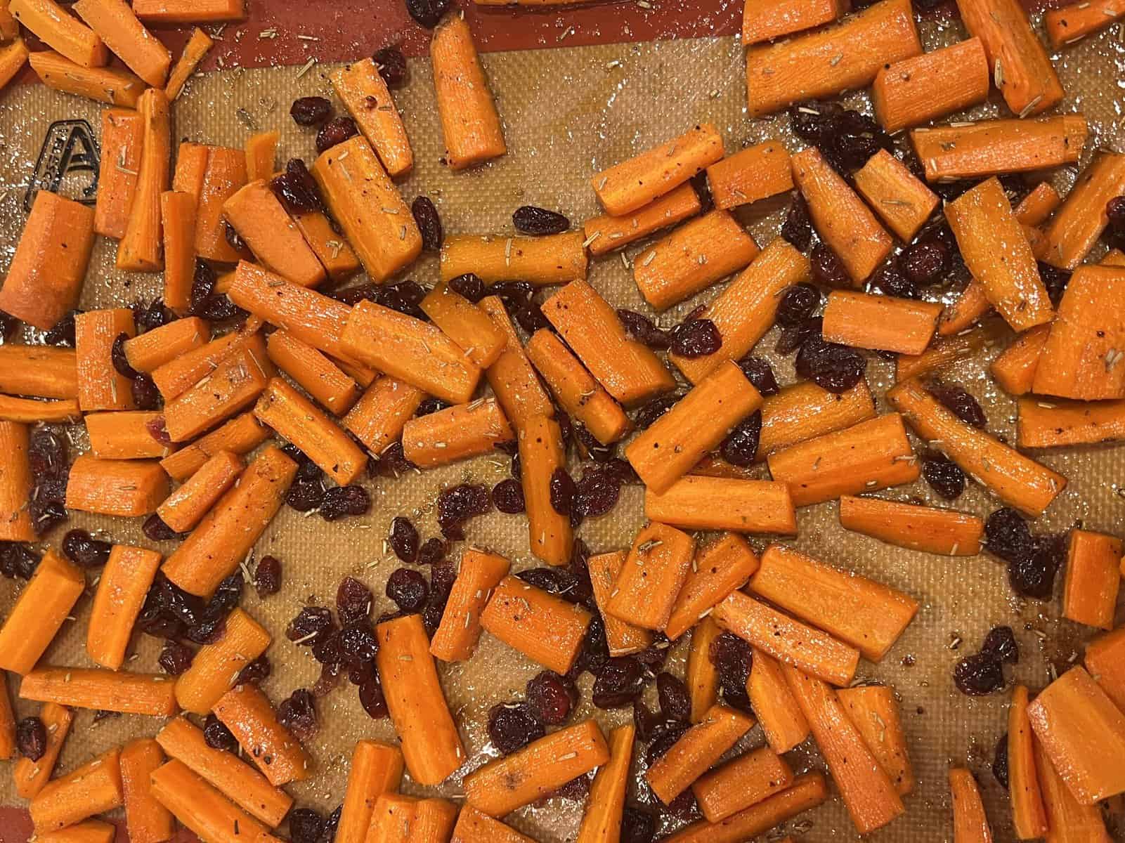 roasted carrots on a baking sheet with dried cranberries and rosemary