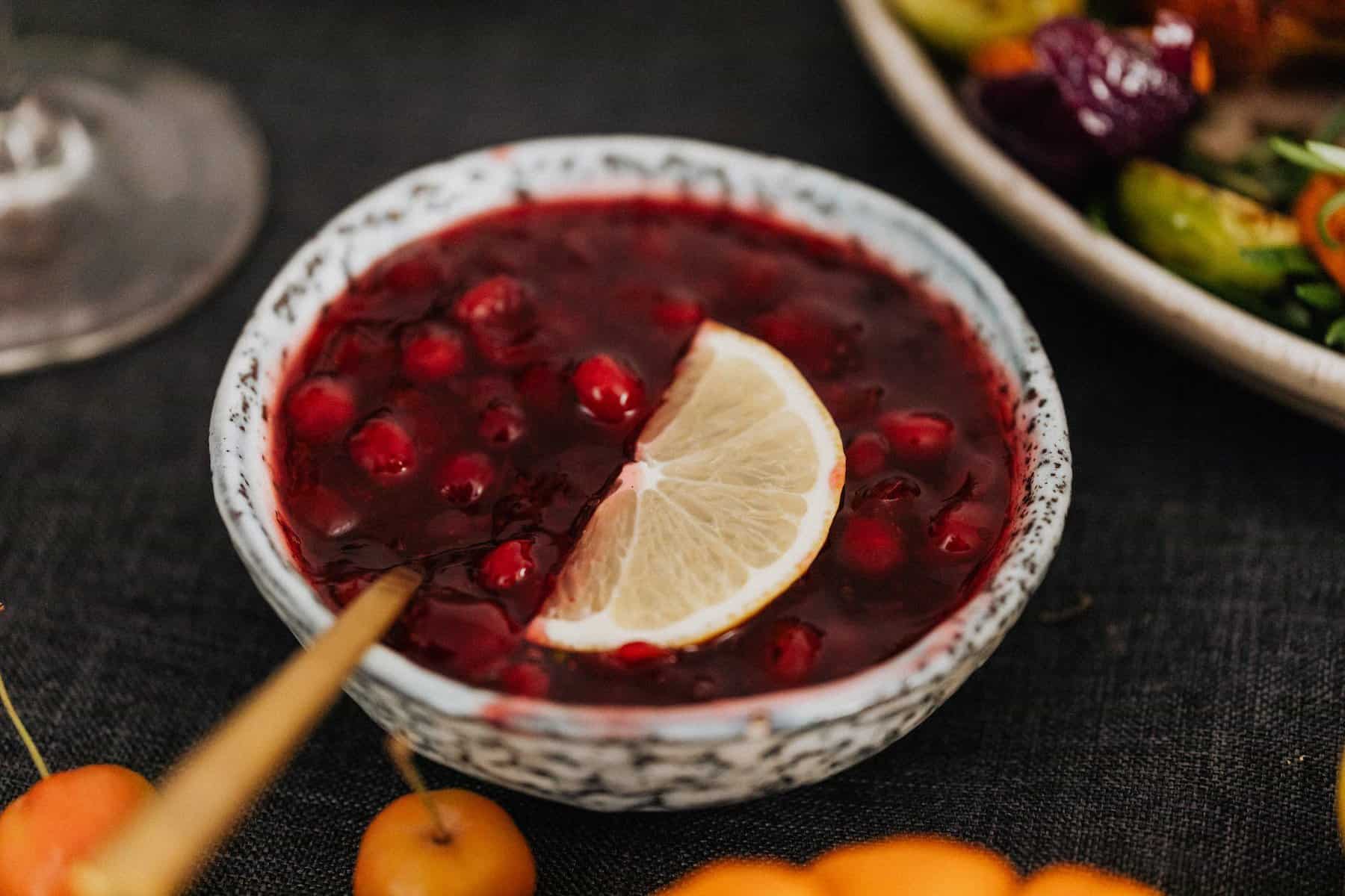 bowl of cranberry sauce with lemon slice and chopstick for ideas on how to use your thanksgiving leftovers
