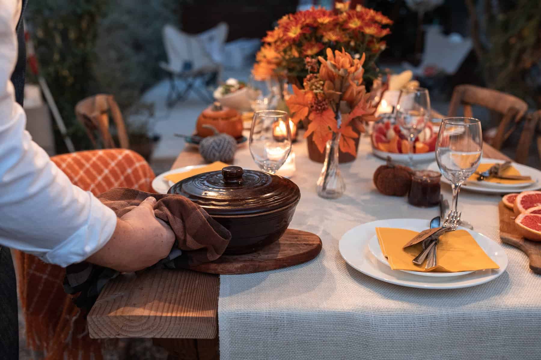 person placing a pot on table during thanksgiving