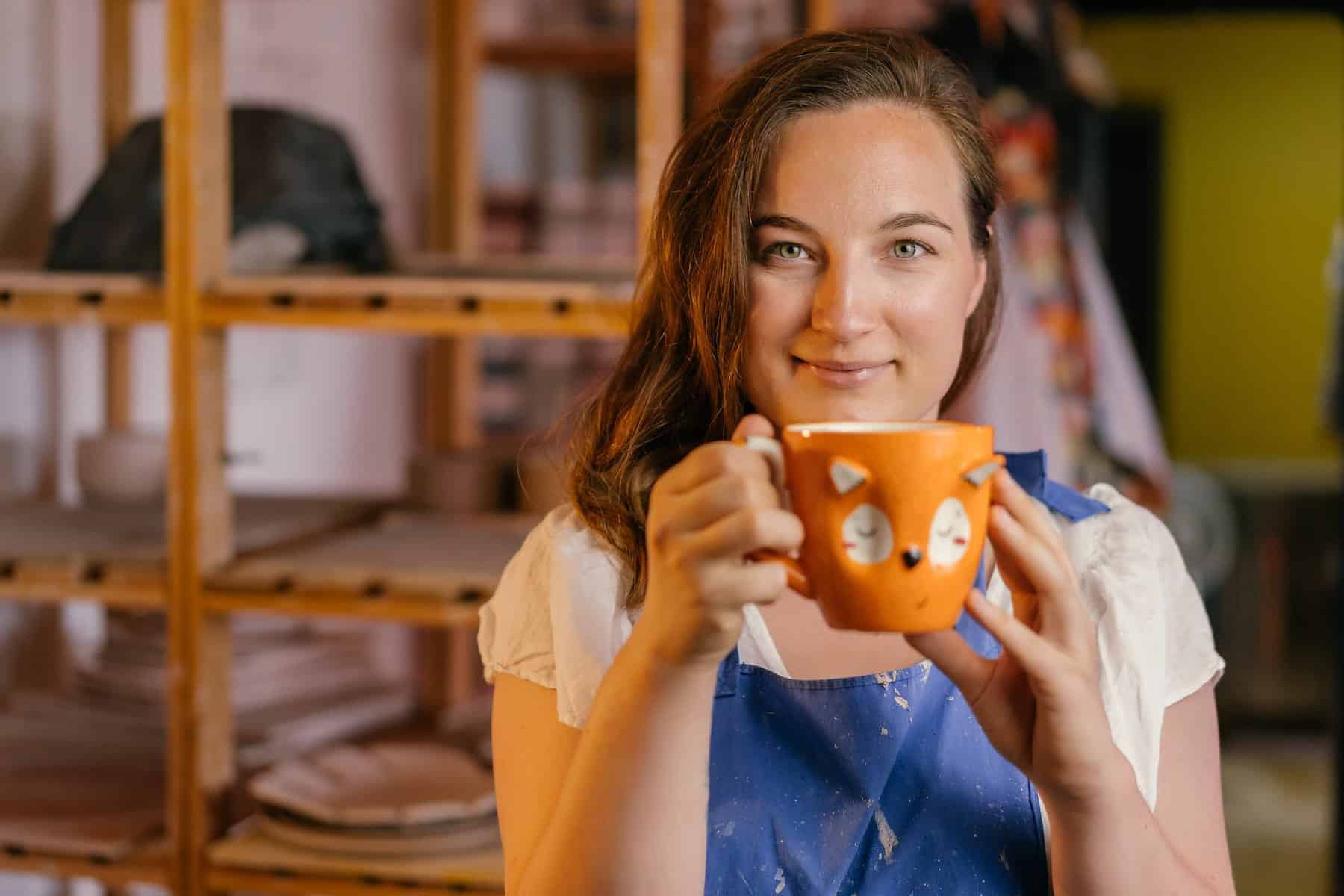 smiling brunette woman with orange mug in hands