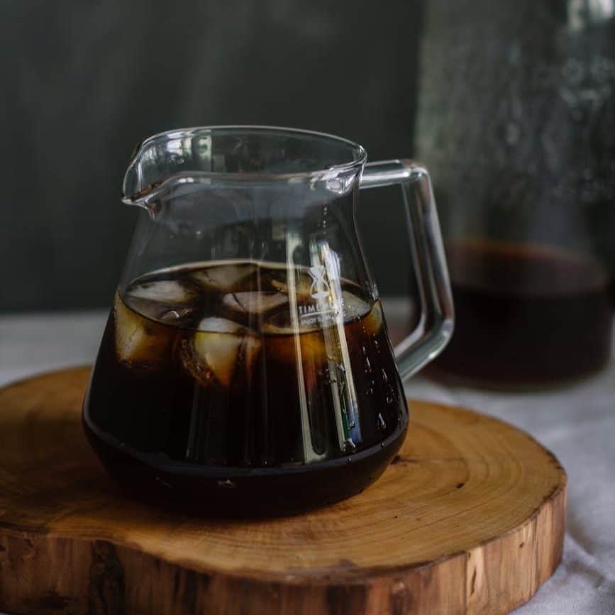clear glass pitcher with cold brew coffee and ice on wooden chopping board