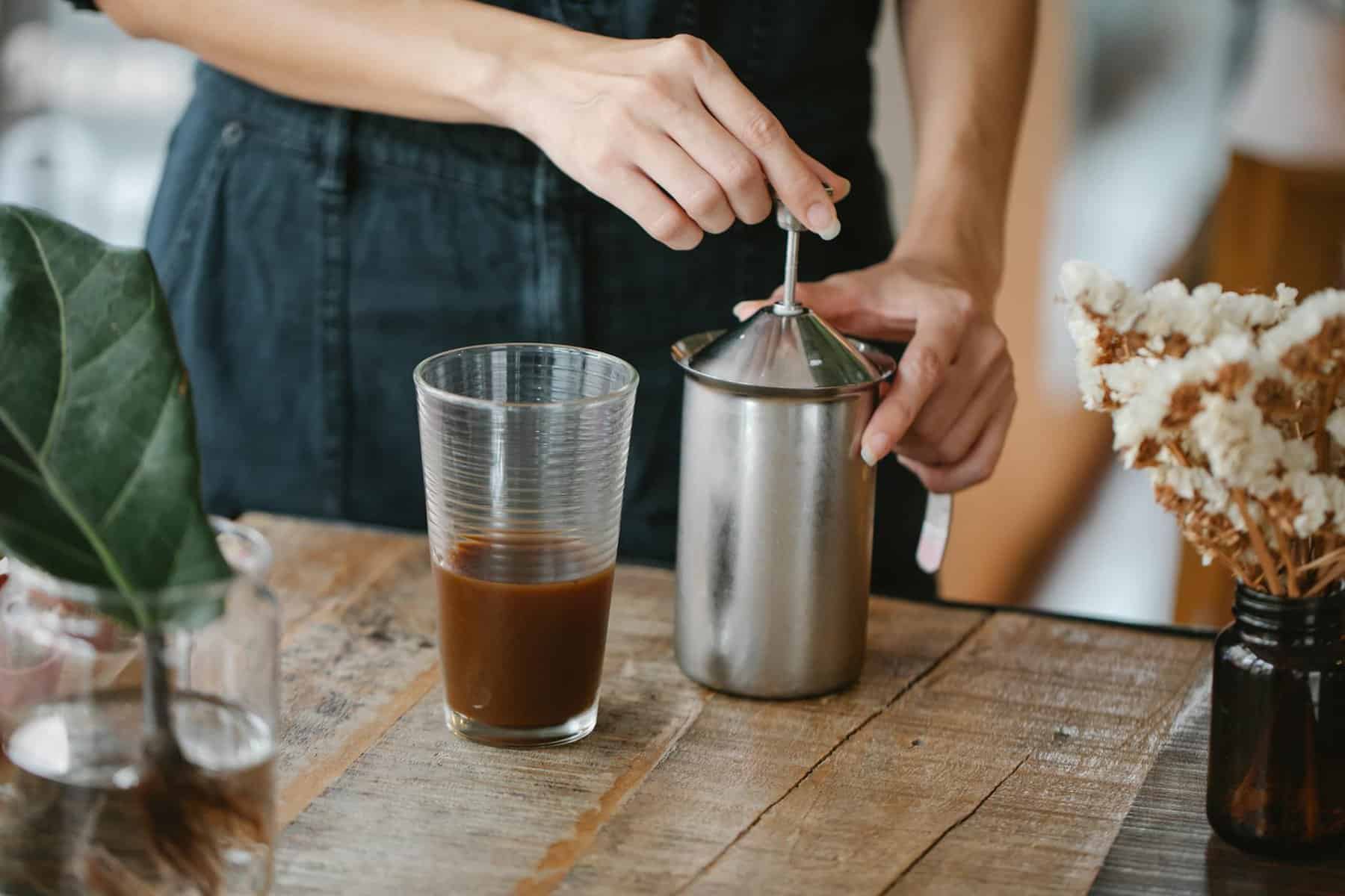 crop unrecognizable woman preparing froth in milk frother for coffee