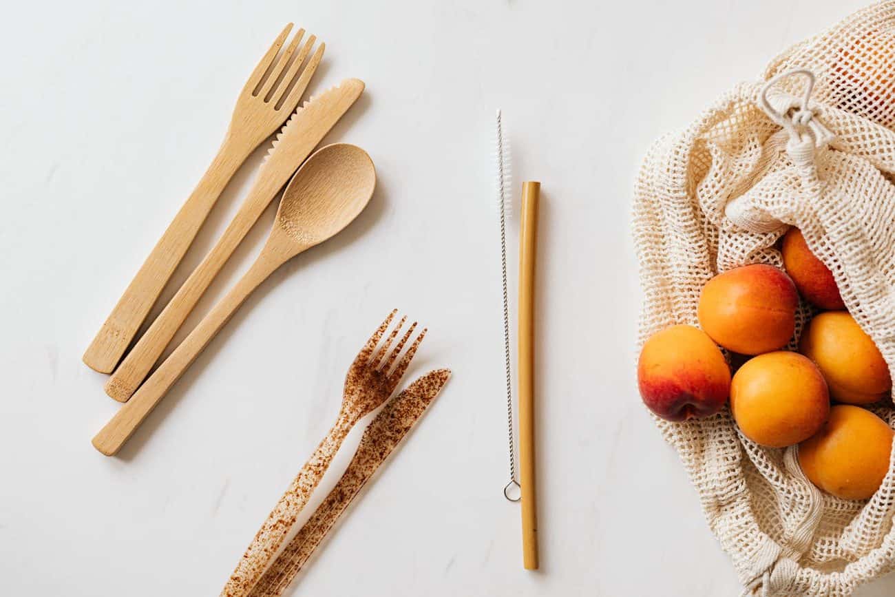 cotton sack with ripe peaches and diverse cutlery on table