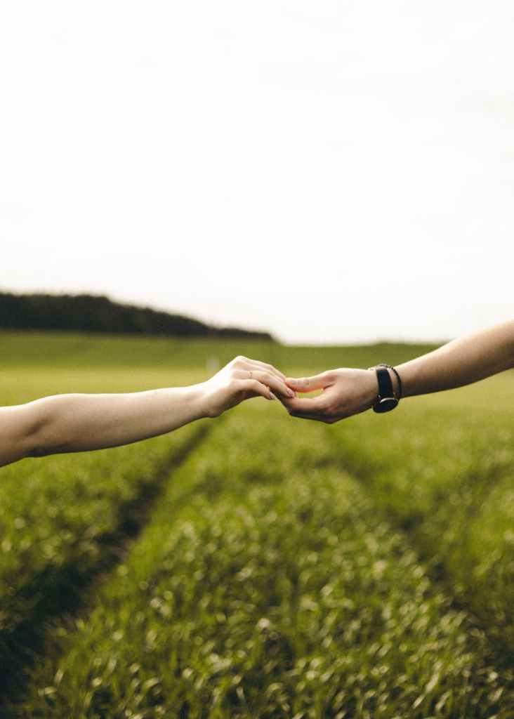 close up of a couple holding hands outdoor on a field