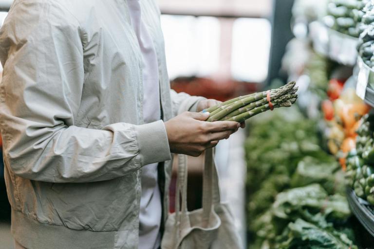 unrecognizable customer with asparagus in supermarket