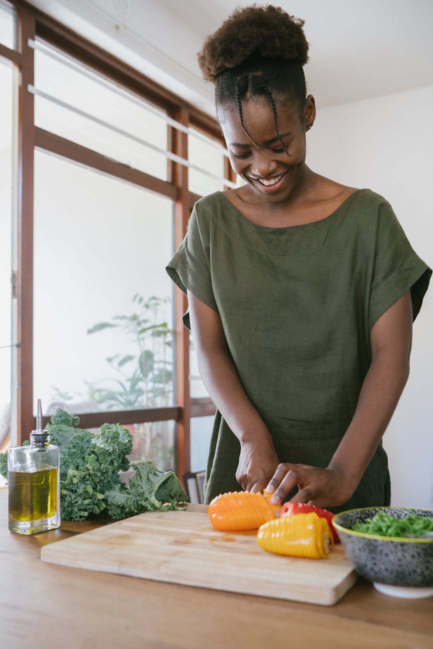 woman in green tank top holding orange bell pepper - learning from sustainable cooking classes online