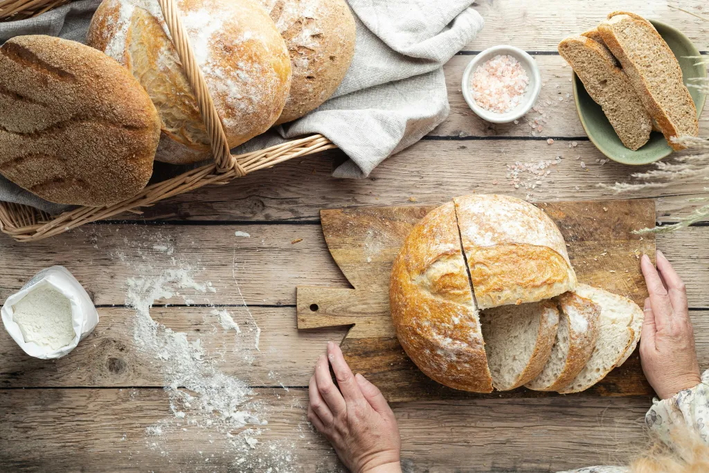 white bread cut on a cutting board and basket with salt and flour