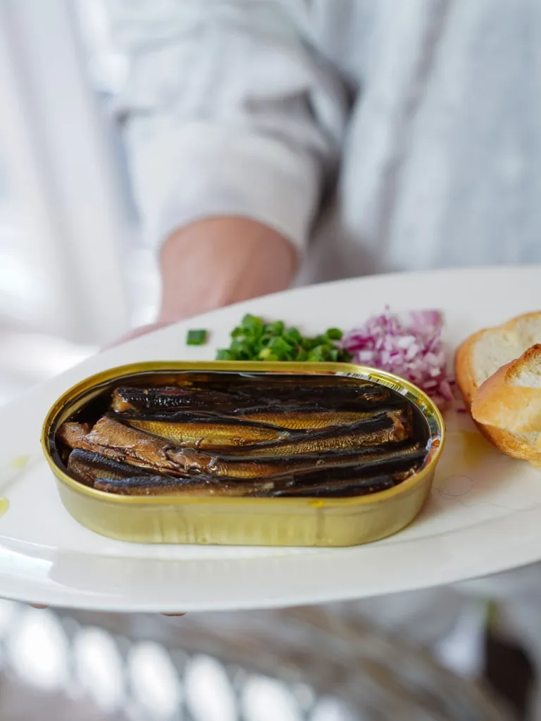 person holding a plate with canned sardine fish